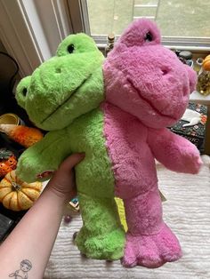 two stuffed animals sitting on top of a bed next to a person's hand