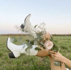 a woman laying on the ground with flowers in her hand and wearing white booties