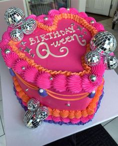 a pink birthday cake with disco balls on it's sides and a heart shaped top