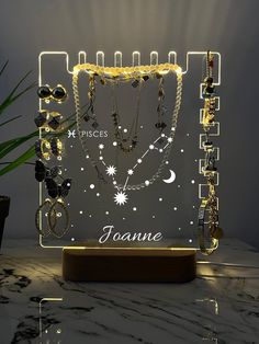 an illuminated jewelry display on a table with a plant in the corner and lights shining from behind it