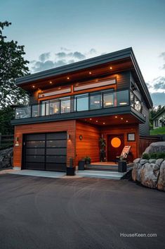 a modern house with wood siding and glass windows on the top floor is lit up at night