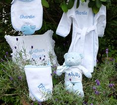 three personalized towels and two teddy bears are sitting in the grass with purple flowers