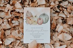 a white card with three pumpkins on it sitting in the middle of some leaves