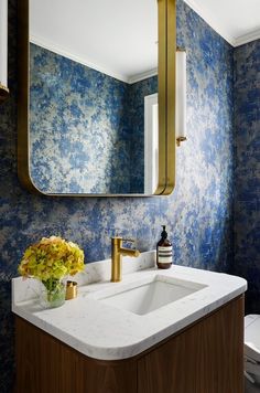 a bathroom with blue wallpaper and gold fixtures