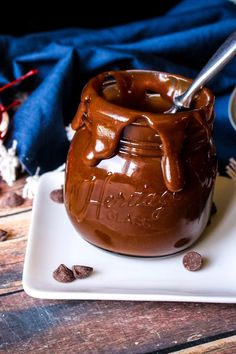 there is a small chocolate pot with spoon in it on a plate next to some cookies