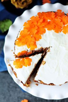 a carrot cake with white frosting and orange flowers on the top is ready to be eaten