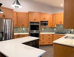 a modern kitchen with stainless steel appliances and wood cabinets, including an island countertop