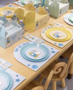 a wooden table topped with lots of plates and napkins covered in blue and yellow paper