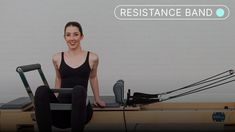 a woman sitting on top of a rowing machine with the resistance band in front of her