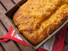 a pan filled with cheesy bread sitting on top of a wooden table next to a red and white towel