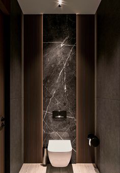 a modern bathroom with black marble walls and flooring, along with a white toilet