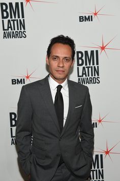 a man in a suit and tie standing on a red carpet at an awards event