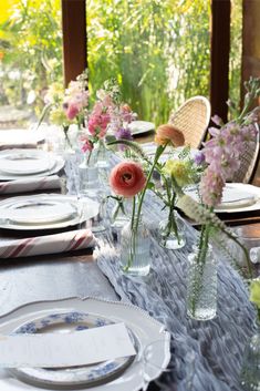 the table is set with plates and flowers in vases on it's sides