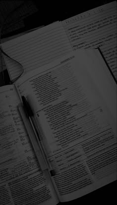 an open book sitting on top of a desk next to a pen