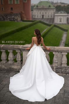 a woman in a white wedding dress standing on a balcony