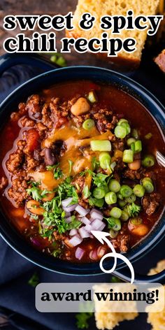 a bowl filled with chili and cheese on top of a blue cloth next to bread