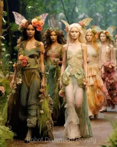 the models are walking down the runway in fairy costumes with flowers on their head and wings