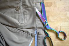 a pair of scissors sitting on top of a piece of cloth next to a pair of pants