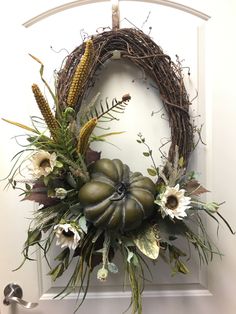 a wreath is hanging on the door with flowers and leaves around it, as well as other decorations