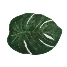 a green and white rug with a large leaf on the top, in front of a white background