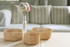 three wicker baskets sitting on top of a table next to a vase with flowers in it