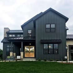 a large gray house sitting on top of a lush green field