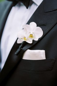 a white flower is placed on the lapel of a black suit