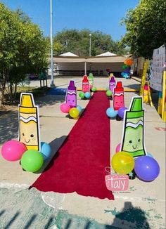 a red carpeted walkway with balloons and paper cutouts on the sides that are shaped like crayons