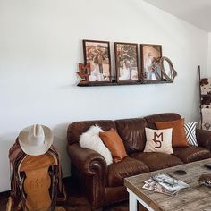 a living room with brown leather couches and pictures on the wall above them,