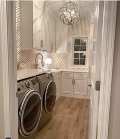 a washer and dryer in a small room with white cabinets on the walls