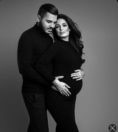 a pregnant couple is posing for a black and white photo with their arms around each other