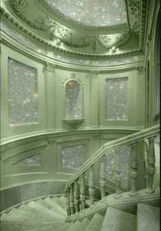 a spiral staircase in an old building with chandelier and windows on the ceiling