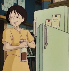 a woman standing in front of a refrigerator holding a cup