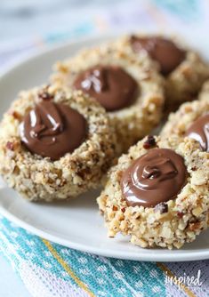 chocolate covered cookies on a white plate with a blue and yellow towel in the background