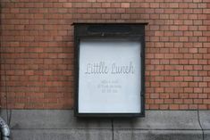 a sign on the side of a brick building that says little lunch in silver lettering