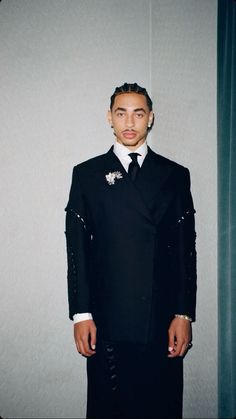 a man wearing a suit and tie standing in front of a wall