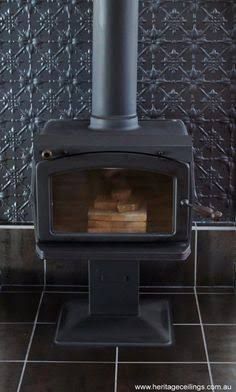 a wood burning stove sitting on top of a tiled floor next to a black wall