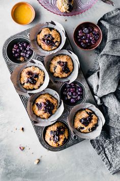 muffins with blueberry filling in the middle on a tray next to other muffins