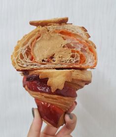 a person holding up a sandwich with peanut butter and jelly