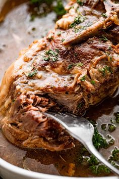 a piece of meat is being cooked in a skillet with a spoon and garnishes