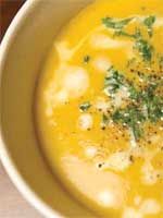 a white bowl filled with soup and garnished with parsley on the top