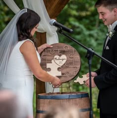 a bride and groom are exchanging their wedding vows in front of a large wooden puzzle