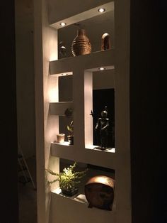 some shelves with vases and other items on them in a dimly lit room at night