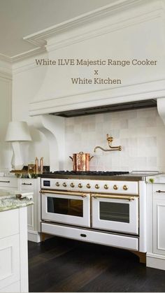 a kitchen with white cabinets and gold accents on the stove top, along with black wood flooring