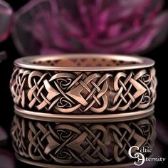 two rings with celtic designs on them sitting in front of some purple flower petals and one is