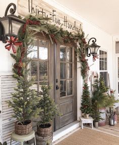 christmas decorations on the front door of a house with wreaths and pine trees in baskets