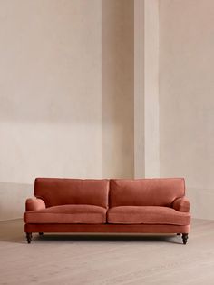 an orange couch sitting on top of a hard wood floor next to a white wall