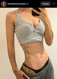 a woman with tattoos on her stomach taking a selfie