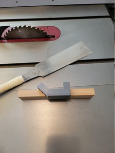 a large knife is laying on top of a piece of wood next to a sharpener