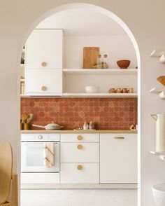 a kitchen with an archway leading to the dining room and sitting area, as well as white cabinets